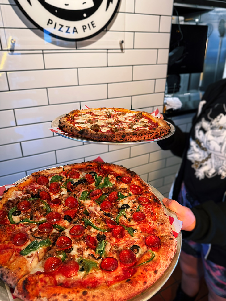 Two specialty pizzas on metal trays.